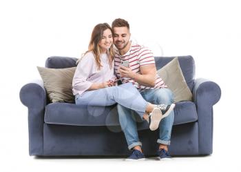 Young couple with mobile phones sitting on sofa against white background�