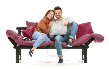 Young couple with laptop sitting on sofa against white background�