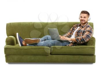 Young man listening to music while sitting on sofa against white background�