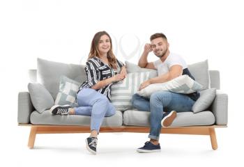 Young couple sitting on sofa against white background�
