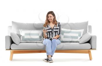 Young woman with mobile phone sitting on sofa against white background�