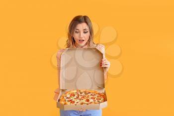 Portrait of surprised young woman with tasty pizza on color background�