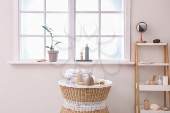 Body care cosmetics with accessories on table and rack in bathroom�