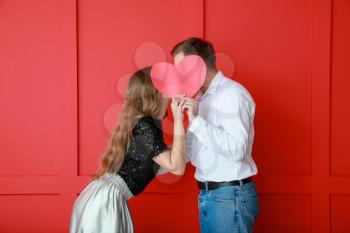 Happy young couple with red heart on color background. Valentine's Day celebration�