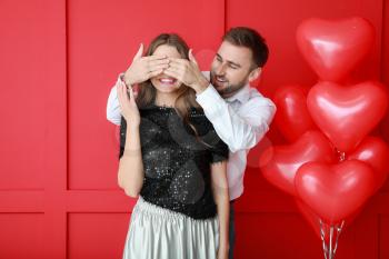 Happy young couple with heart-shaped balloons on color background. Valentine's Day celebration�