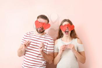 Happy young couple with red hearts on color background. Valentine's Day celebration 