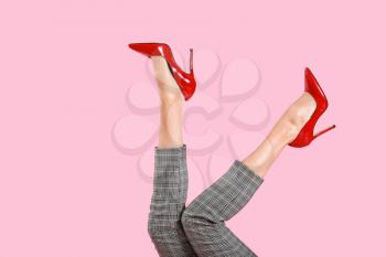 Legs of young woman in high-heeled shoes on color background 
