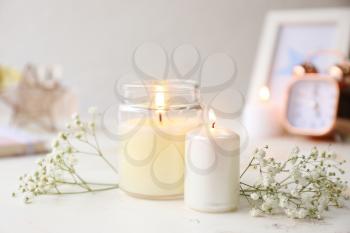 Glowing candles with flowers on white table�
