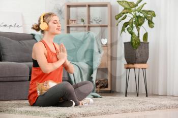 Young woman with cute cat practicing yoga at home�