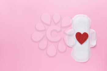 Menstrual pad with red heart on color background. Menstruation concept�