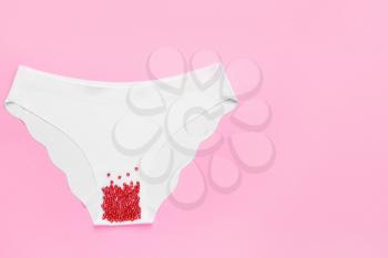 Female panties with red beads on color background. Menstruation concept�