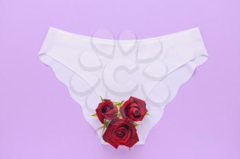 Female panties with red flowers on color background. Menstruation concept�