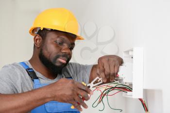 African-American electrician performing wiring in room�