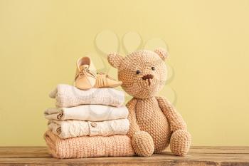 Stack of baby clothes and toy on table�