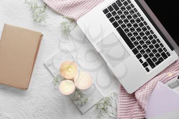 Burning candles, flowers and laptop on table�