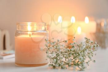 Beautiful burning candle and flowers on table�