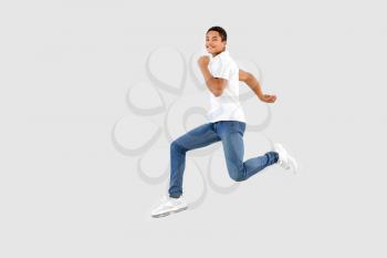 Jumping African-American teenager boy on white background�