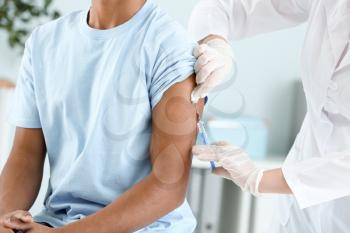 Doctor vaccinating teenage boy in clinic, closeup�