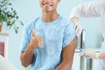 Doctor vaccinating teenage boy in clinic�