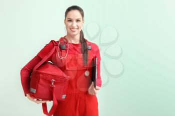 Female paramedic with bag on color background�