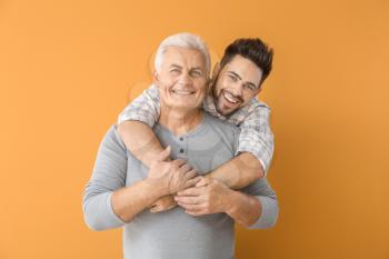 Young man and his father on color background�