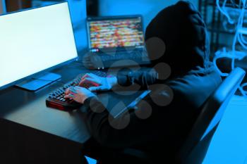 Professional hacker using computer in dark room�