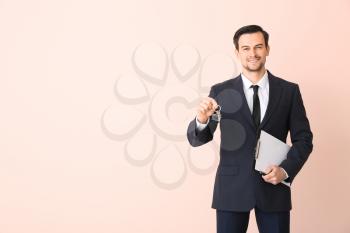 Male real estate agent with key on color background�
