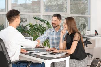 Bank manager shaking hands with couple in office�