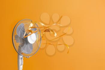 Electric fan with fluttering ribbons on color background�