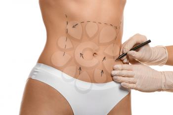 Plastic surgeon applying marks on female body against white background�
