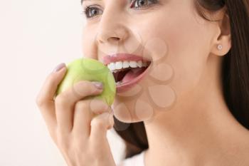 Beautiful young woman with fresh apple on light background�