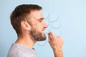 Young man with chewing gum on color background�