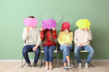 Group of young people with blank speech bubbles near color wall�