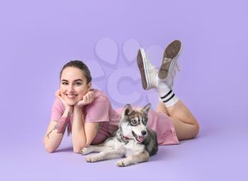 Cute woman with funny husky puppy on color background�