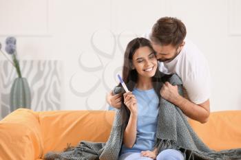 Happy young couple with pregnancy test at home�