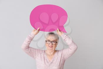 Senior woman with blank speech bubble on grey background�