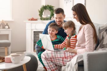 Happy family with laptop resting at home�