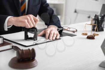 Male lawyer with stamp and document in office�