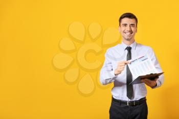 Male bank manager with document on color background�