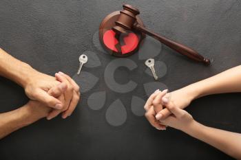 Hands of couple with keys and judge's gavel on dark background. Concept of divorce�