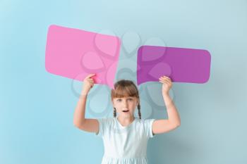 Surprised little girl with blank speech bubbles on color background�