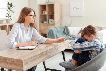 Female psychologist working with sad boy in office�