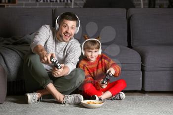 Father and his little daughter playing video games at home in evening�
