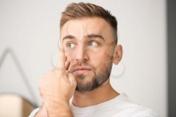 Young man putting in contact lenses at home�