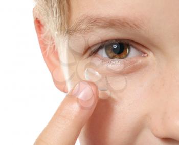 Little boy putting in contact lens on white background, closeup�