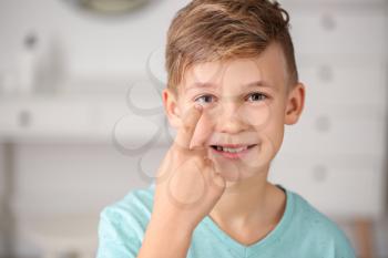 Little boy putting in contact lens at home�