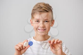 Little boy with contact lens case and eyeglasses on grey background�