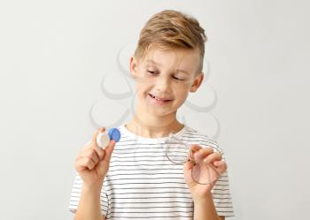 Little boy with contact lens case and eyeglasses on grey background�