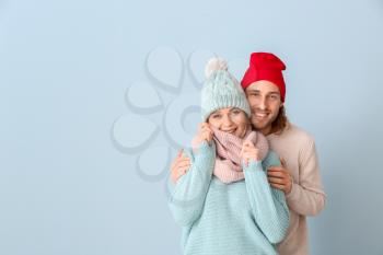 Happy couple in winter clothes on color background�