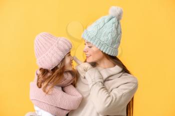 Woman and her little daughter in winter clothes on color background�